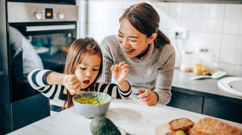 母和女制作guacamole,展示如何让孩子们通过让他们参与烹饪来吃蔬菜